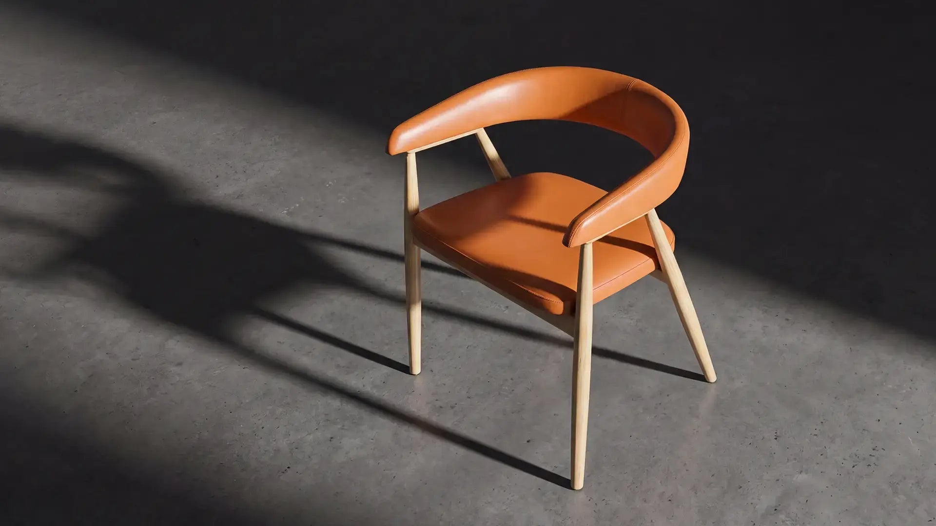A tan leather and light wood café chair on a concrete floor